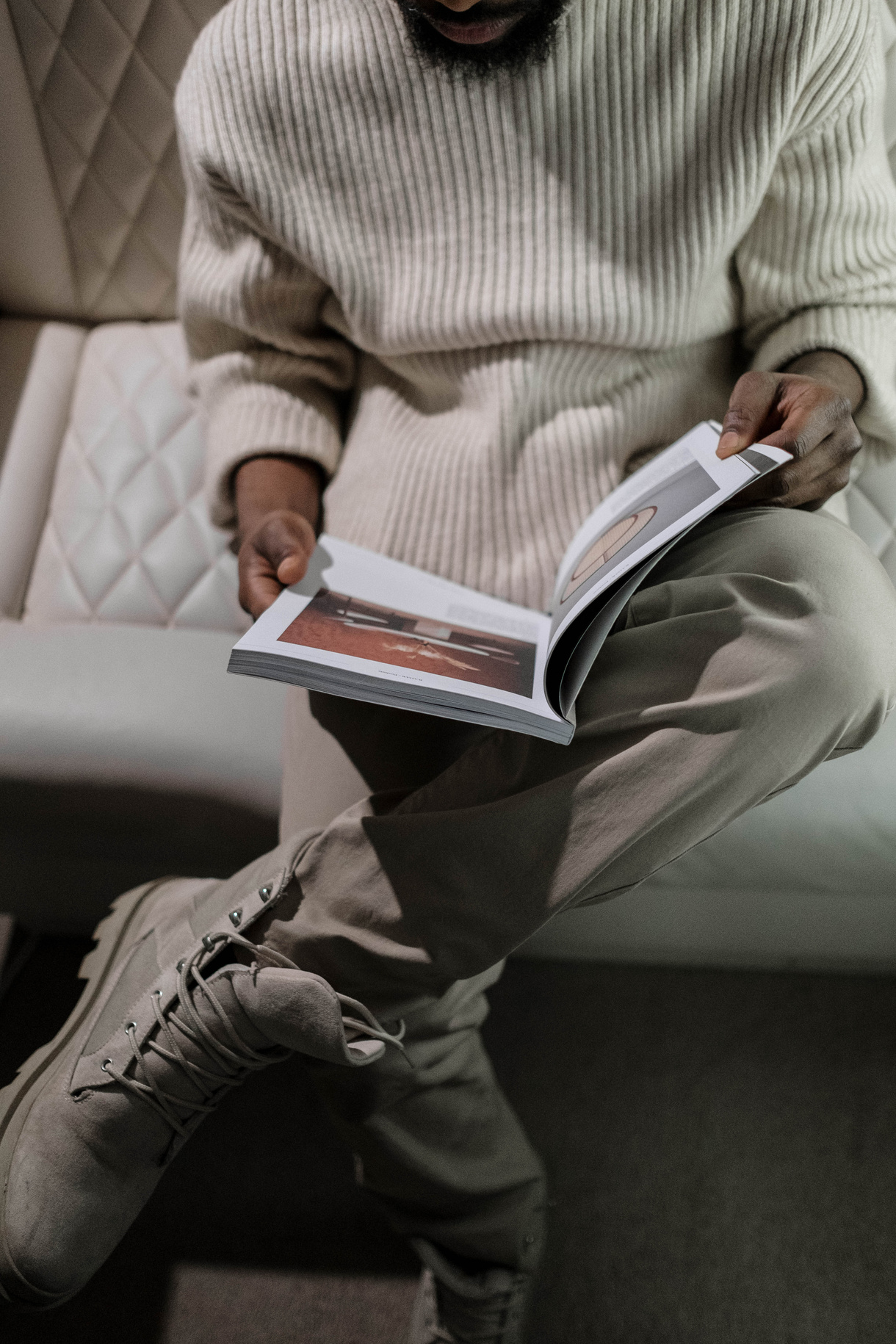 Person in Gray and White Striped Long Sleeve Shirt and Gray Pants Sitting on Couch